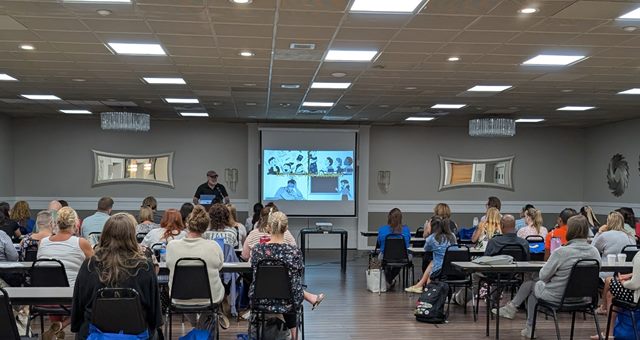 Dr. Gavoni presenting to a large seated audience of educators at a leadership training session